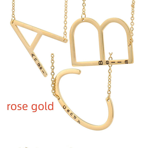Collier en acier titane doré rose avec pendentifs lettres évidées et chaîne à maillons.