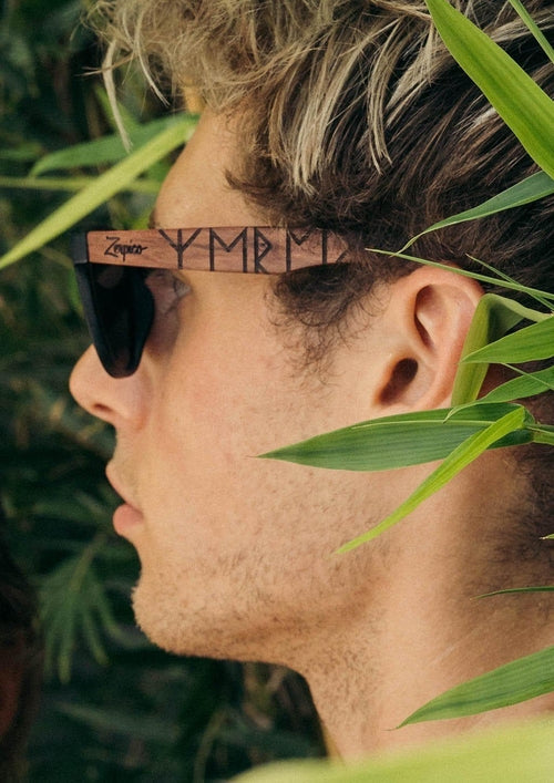 Lunettes de soleil sur visage masculin, branches en bois gravées, verres foncés