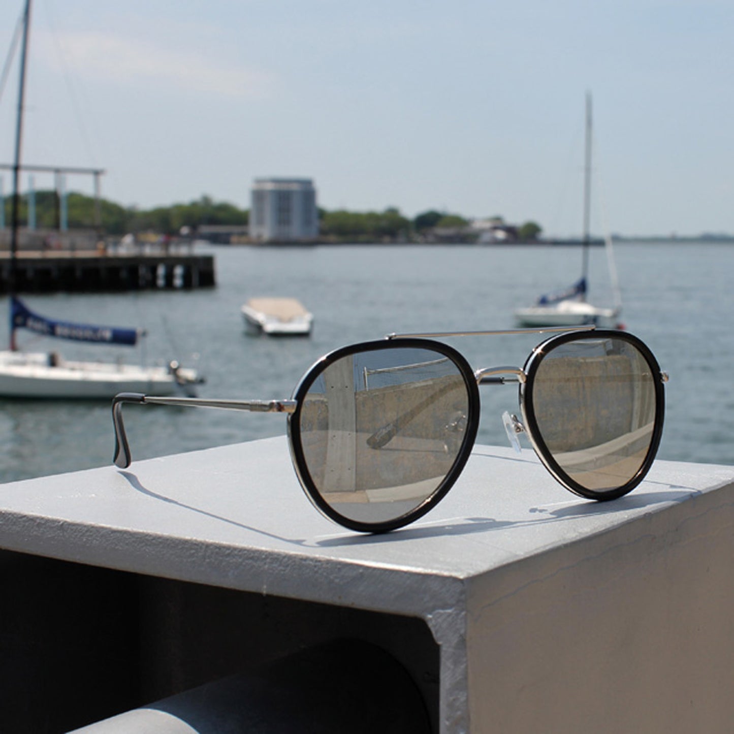 Lunettes de soleil unisex, monture noire, verres gris, branches argent, angle trois-quarts.