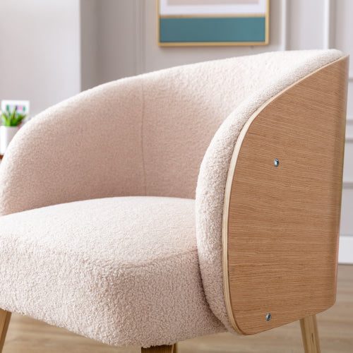Fauteuil beige en laine d’agneau, pieds en bois courbé, dossier arrondi.