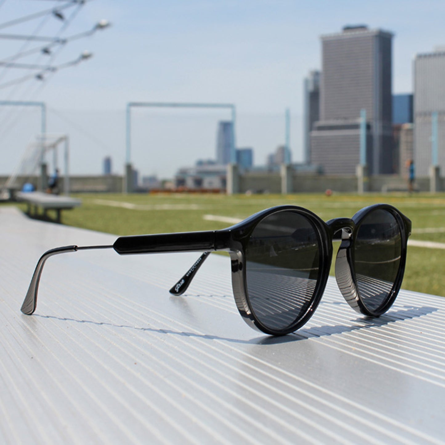 Lunettes de soleil noires, verres fumés, posées sur une surface claire