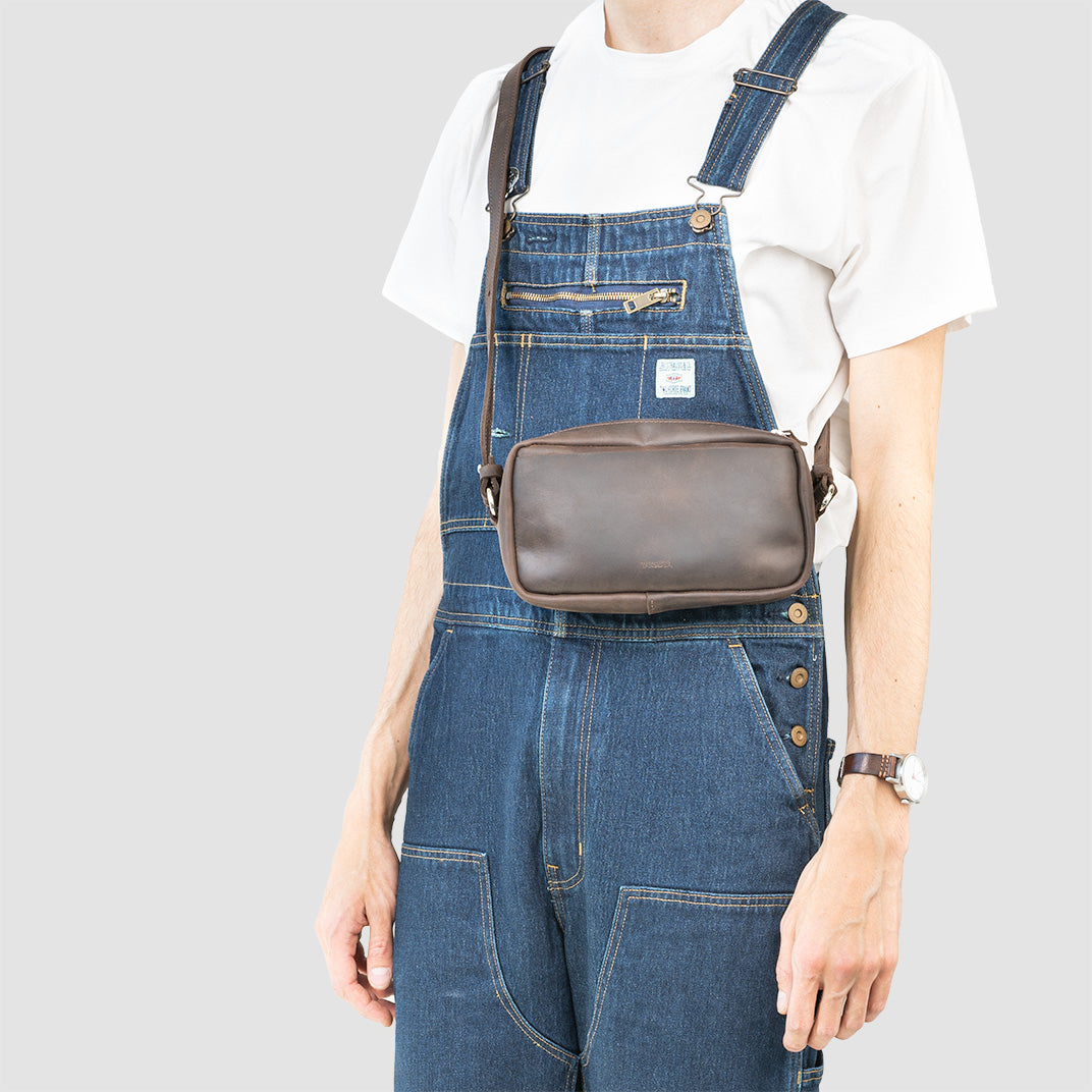 Mini sac besace en cuir noir porté en bandoulière par un modèle