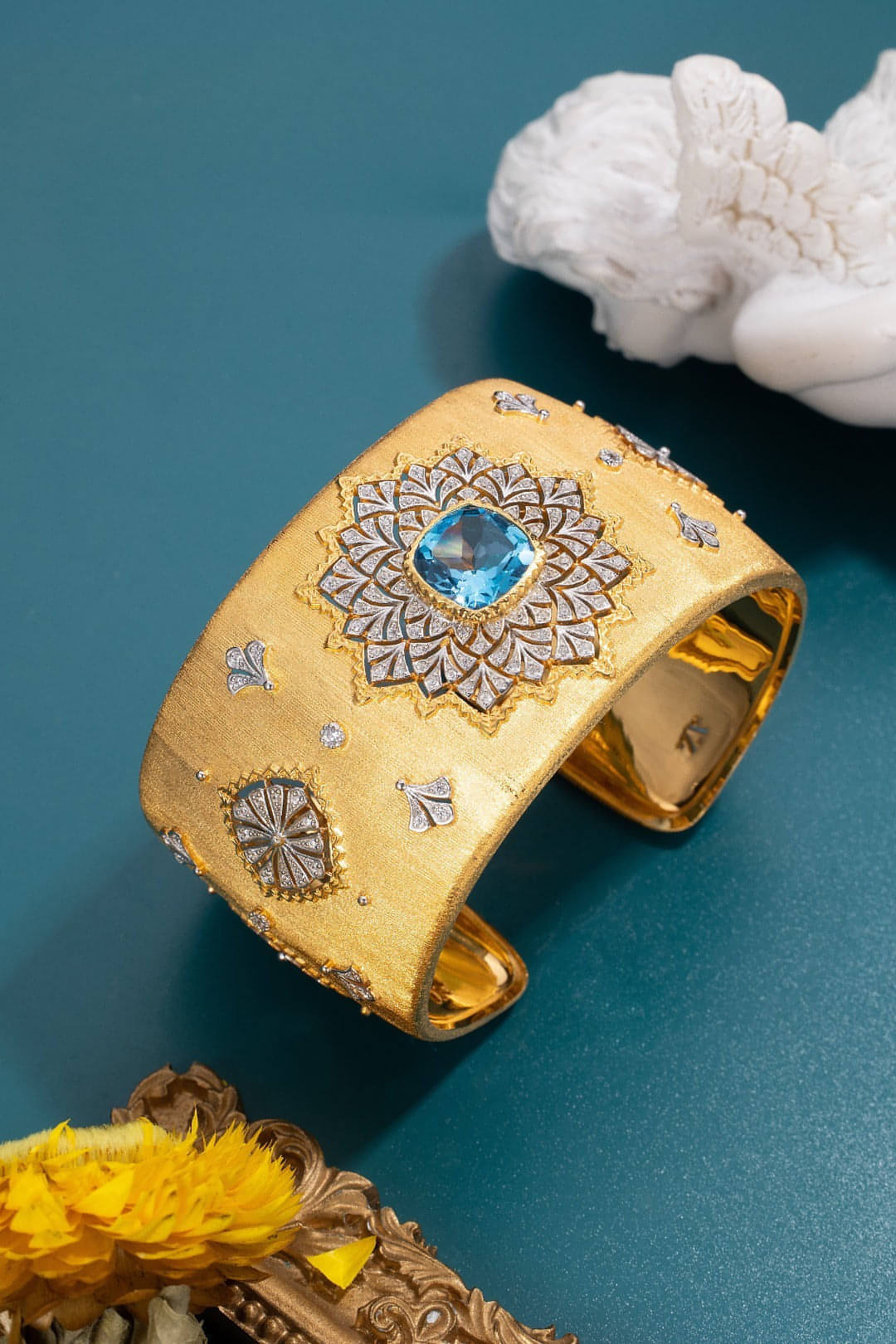 Bracelet manchette doré avec grande fleur ciselée autour de la pierre bleue