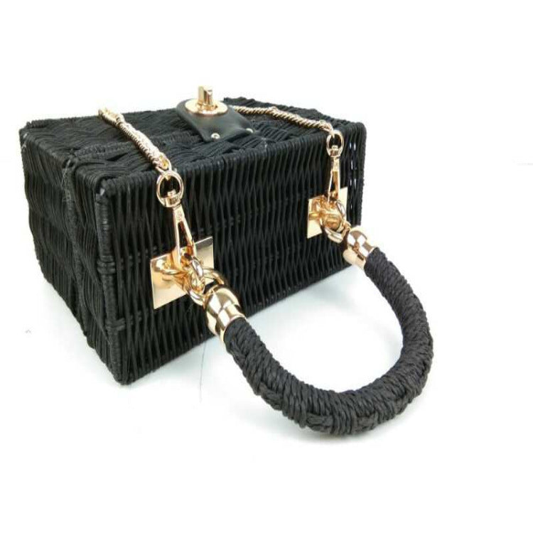Sac boîte en raphia noir tressé, bandoulière chaîne dorée et anse torsadée.