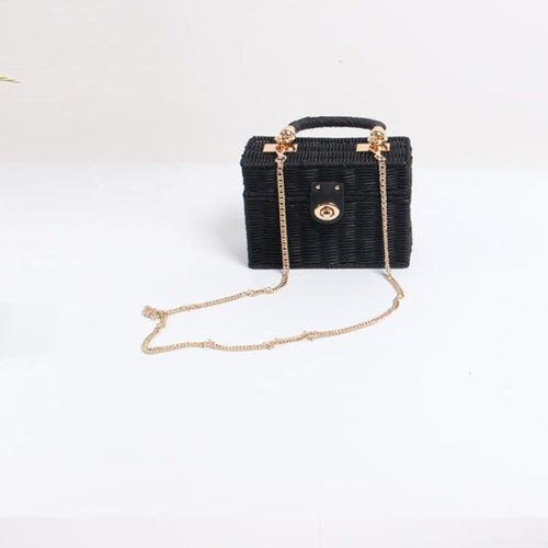 Sac boîte en raphia noir tressé, bandoulière fine dorée et bouton central.