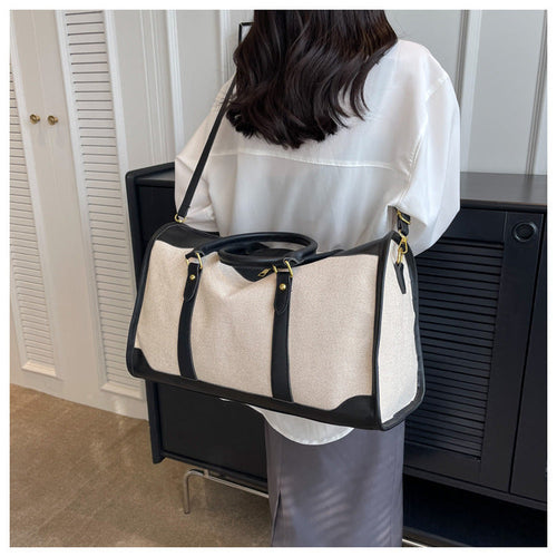 Sac de voyage en toile beige, anses et lanières noires, grande contenance