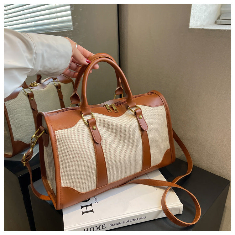 Sac cabas de voyage en toile bicolore, vue rapprochée avec sangles et anneaux dorés
