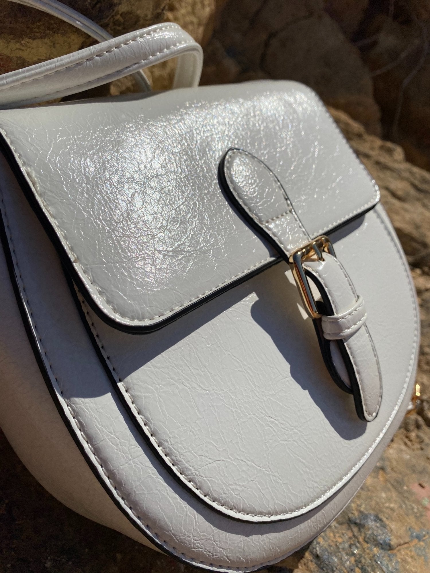 Mini sac à boucle blanc en simili cuir avec fermoir doré sur le rabat.