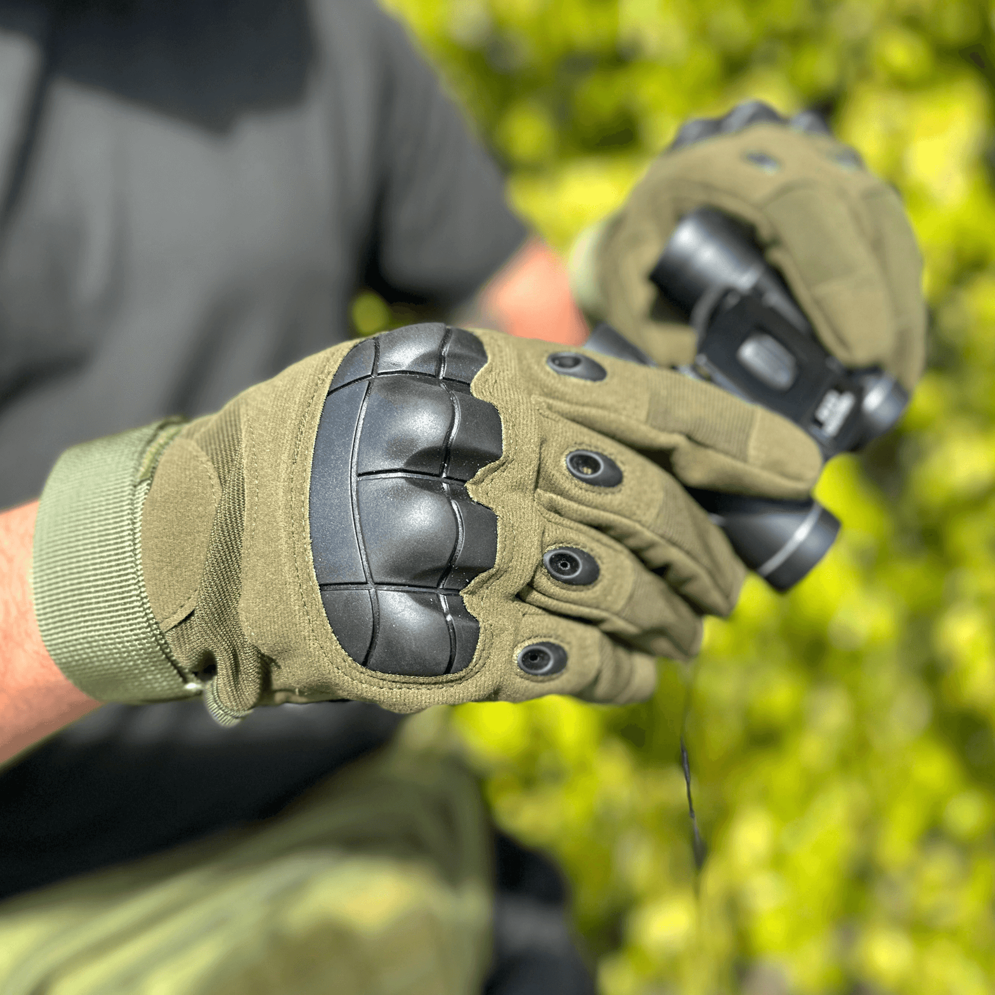 Gants tactiques kaki portés, zoom sur les protections noires et les passants.