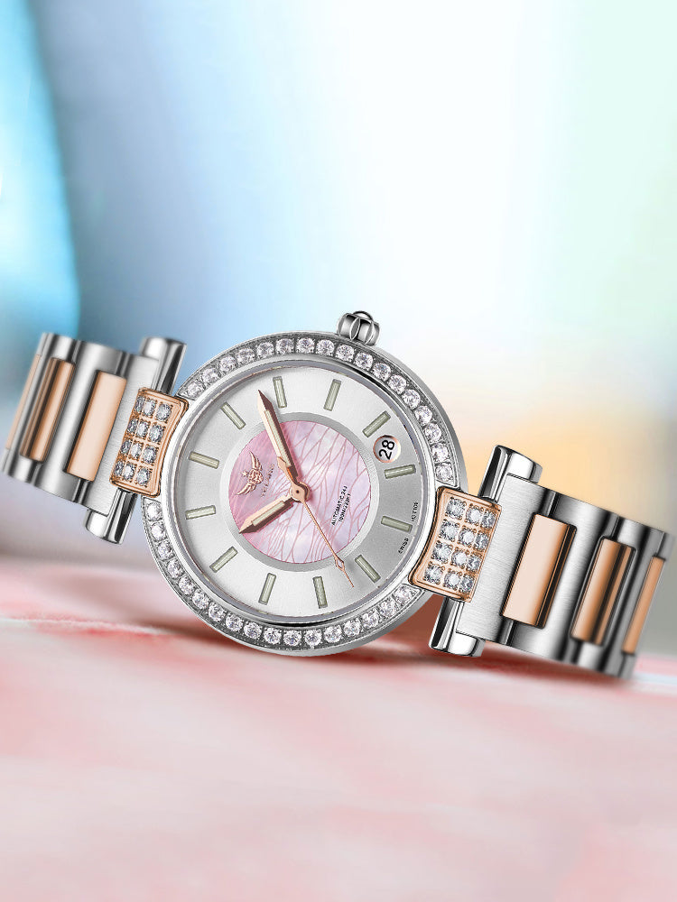 Montre femme Hemys cadran rose pâle, lunette sertie de pierres, bracelet acier bicolore.