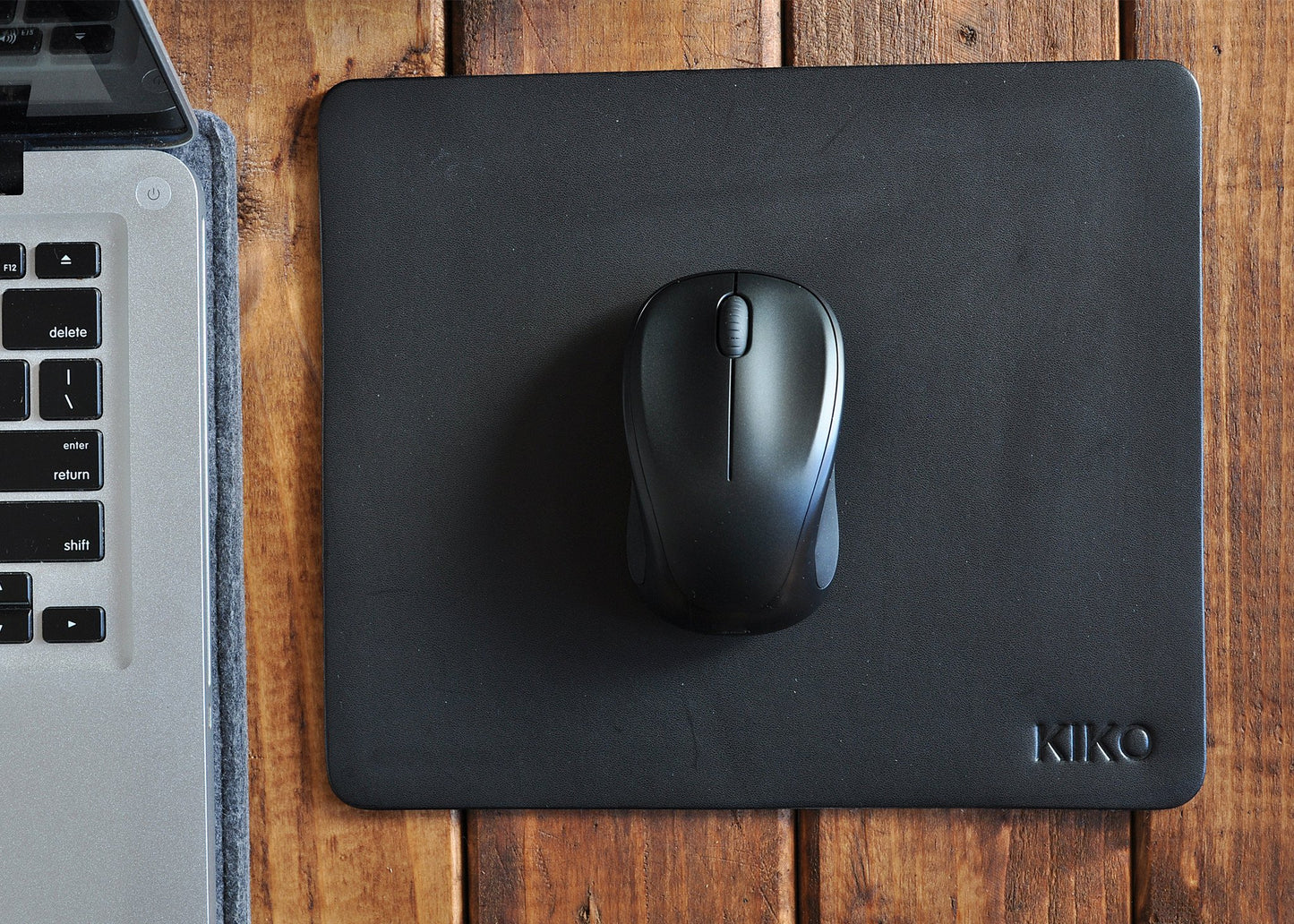 Tapis de souris en cuir noir avec souris noire, logo KIKO en bas à droite.