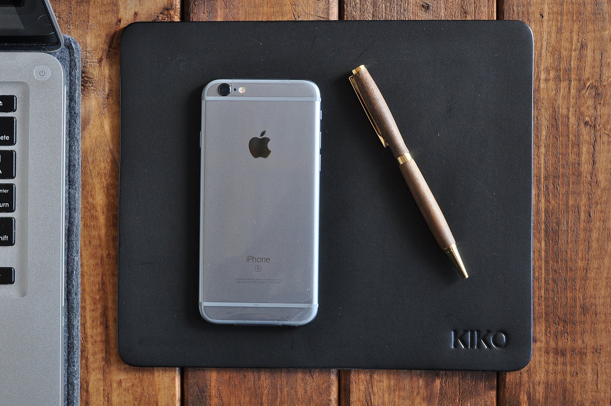 Tapis de souris en cuir noir avec smartphone argenté et stylo, logo KIKO en bas à droite.