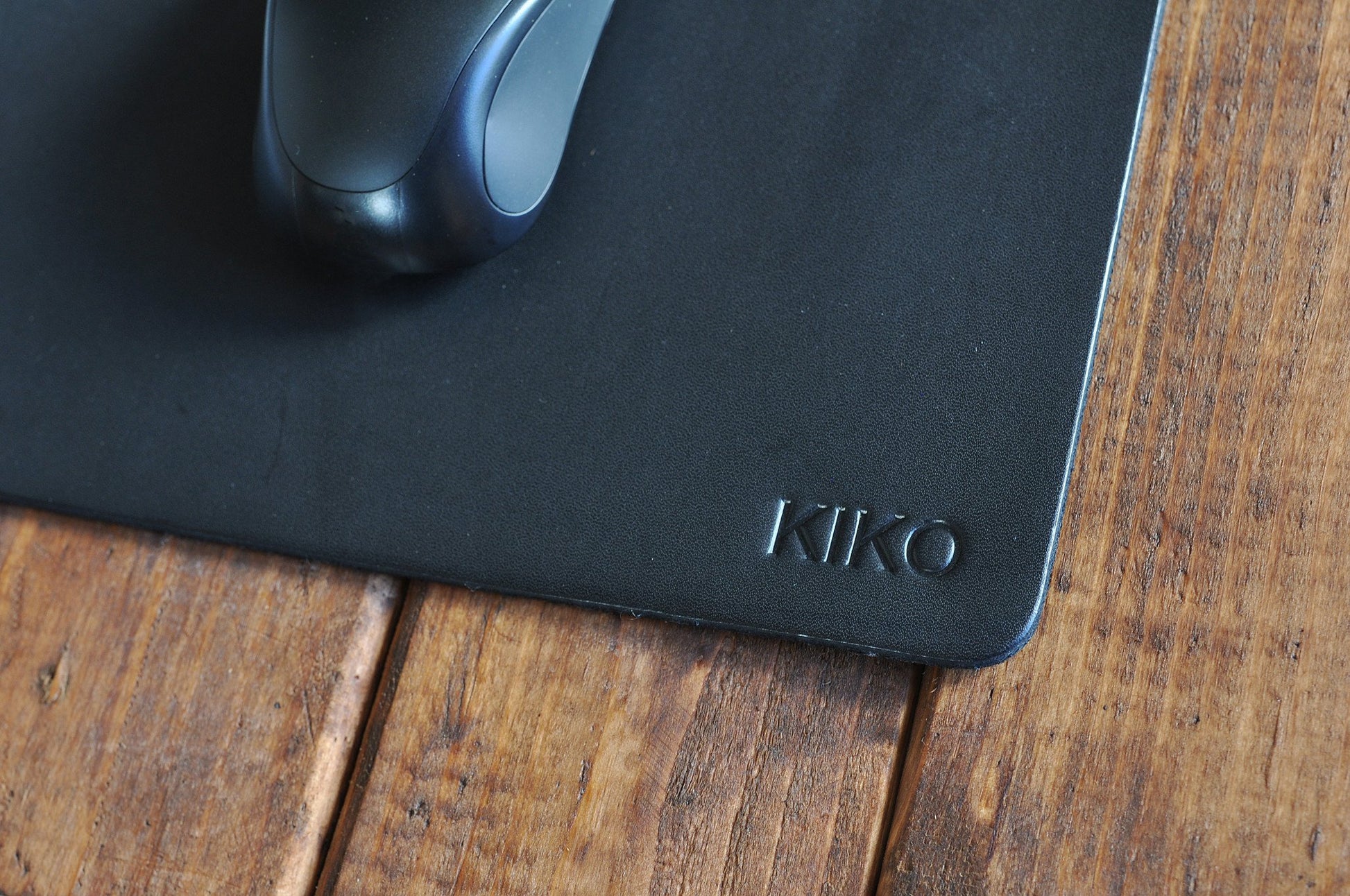 Angle du tapis de souris en cuir noir avec souris visible en haut, logo KIKO en bas.