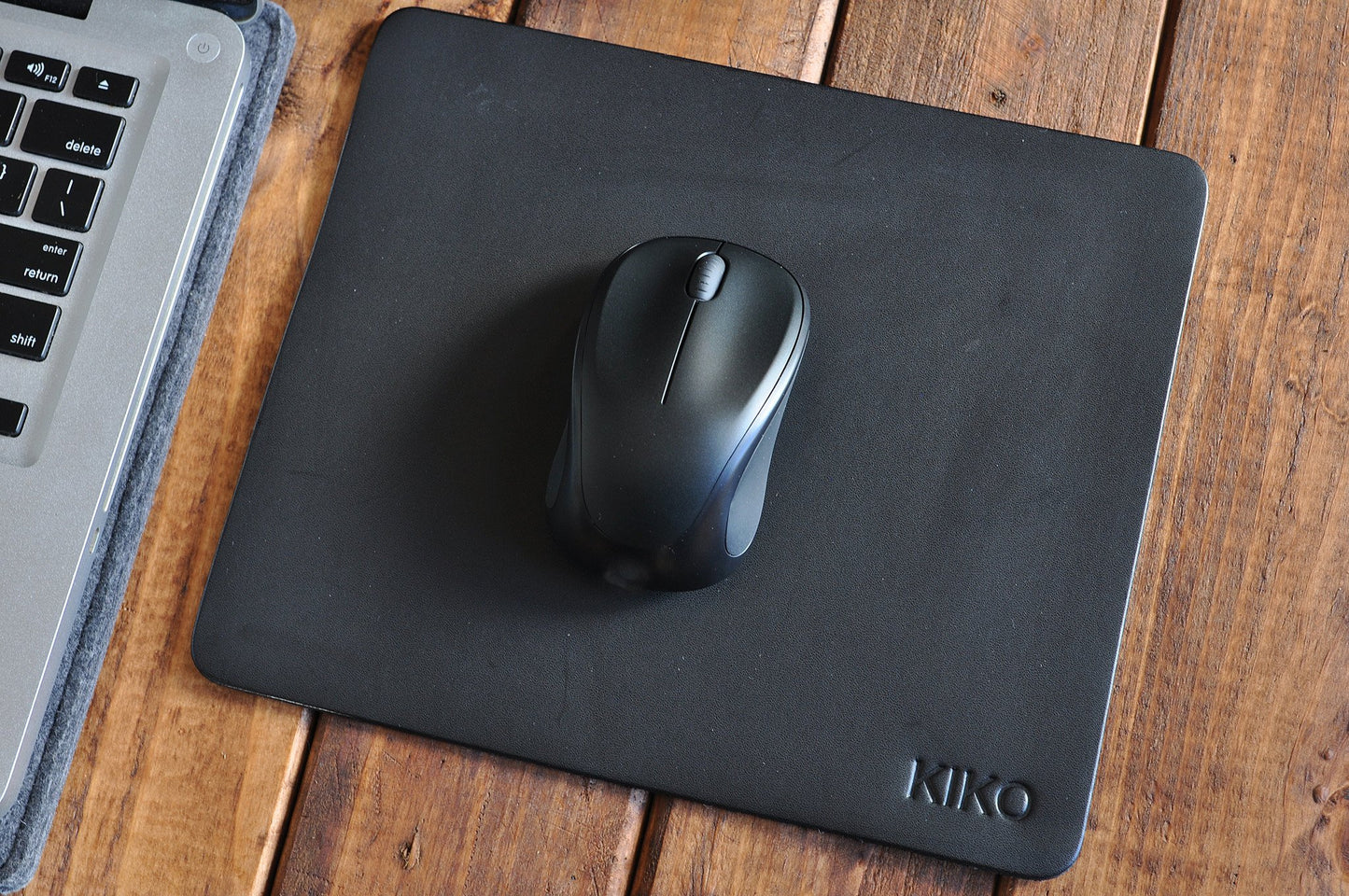 Tapis de souris en cuir noir avec souris noire, logo KIKO en bas à droite.