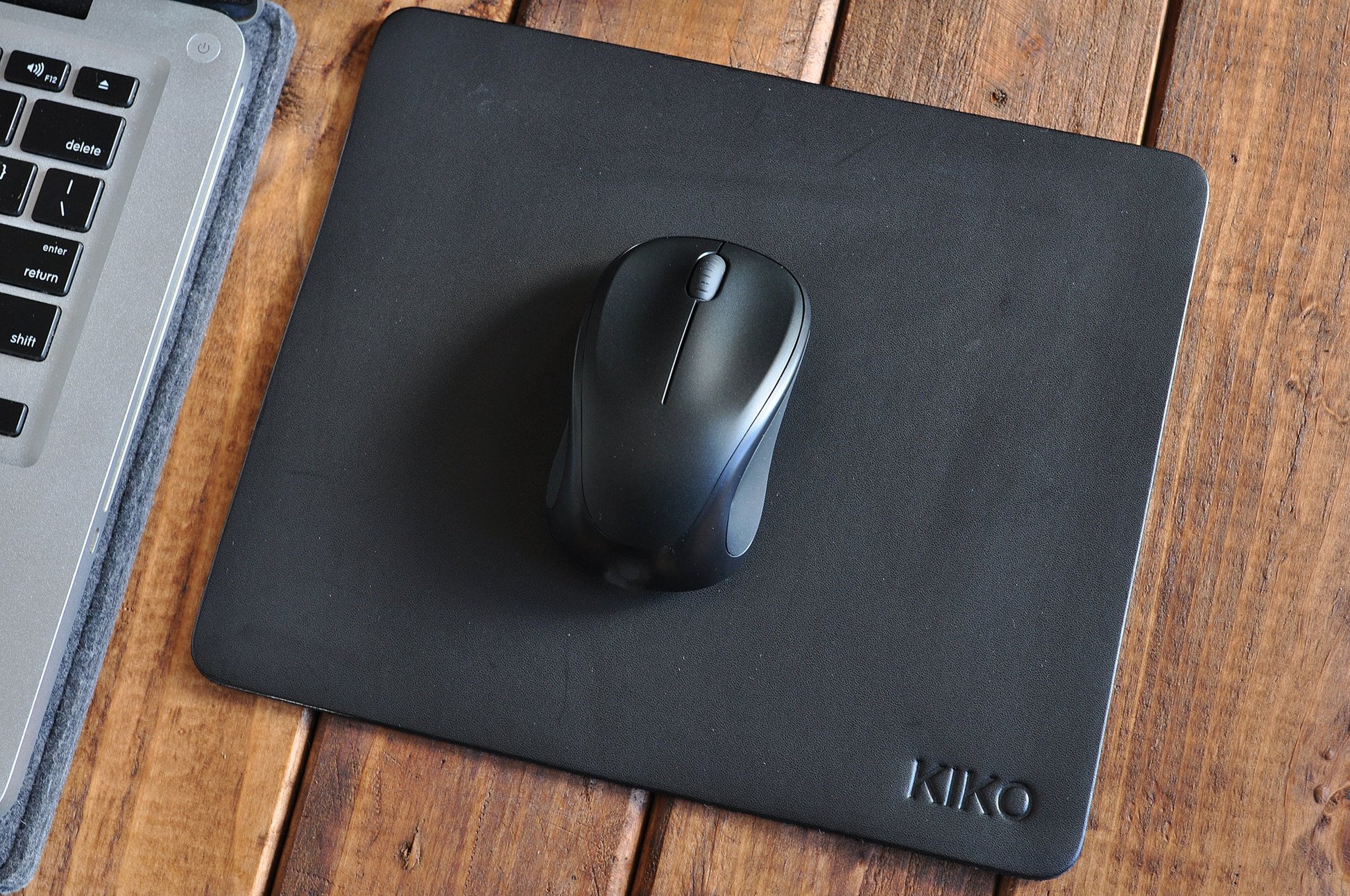 Tapis de souris en cuir noir avec souris noire, logo KIKO en bas à droite.
