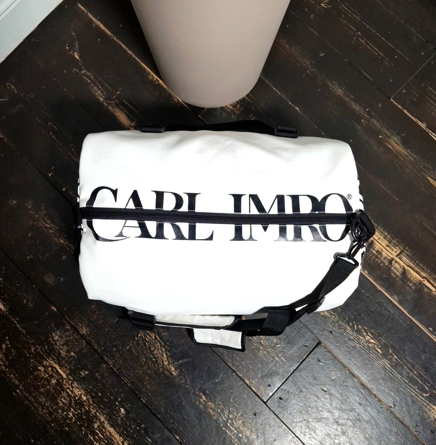 Sac en cuir blanc à poignée et bandoulière noires, devant imprimé en lettres et rayures.