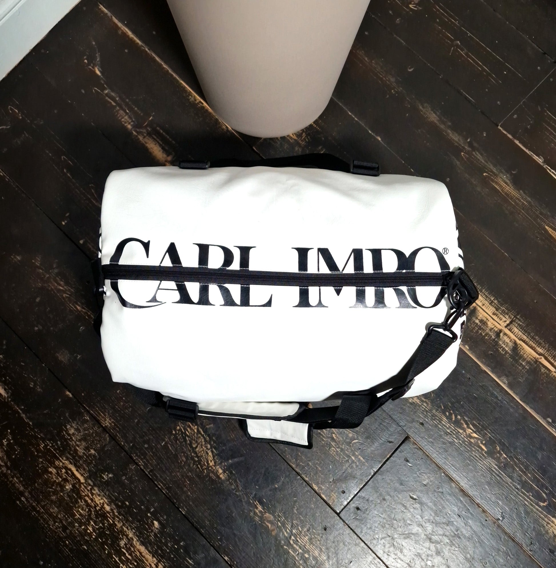 Sac en cuir blanc à poignée et bandoulière noires, devant imprimé en lettres et rayures.