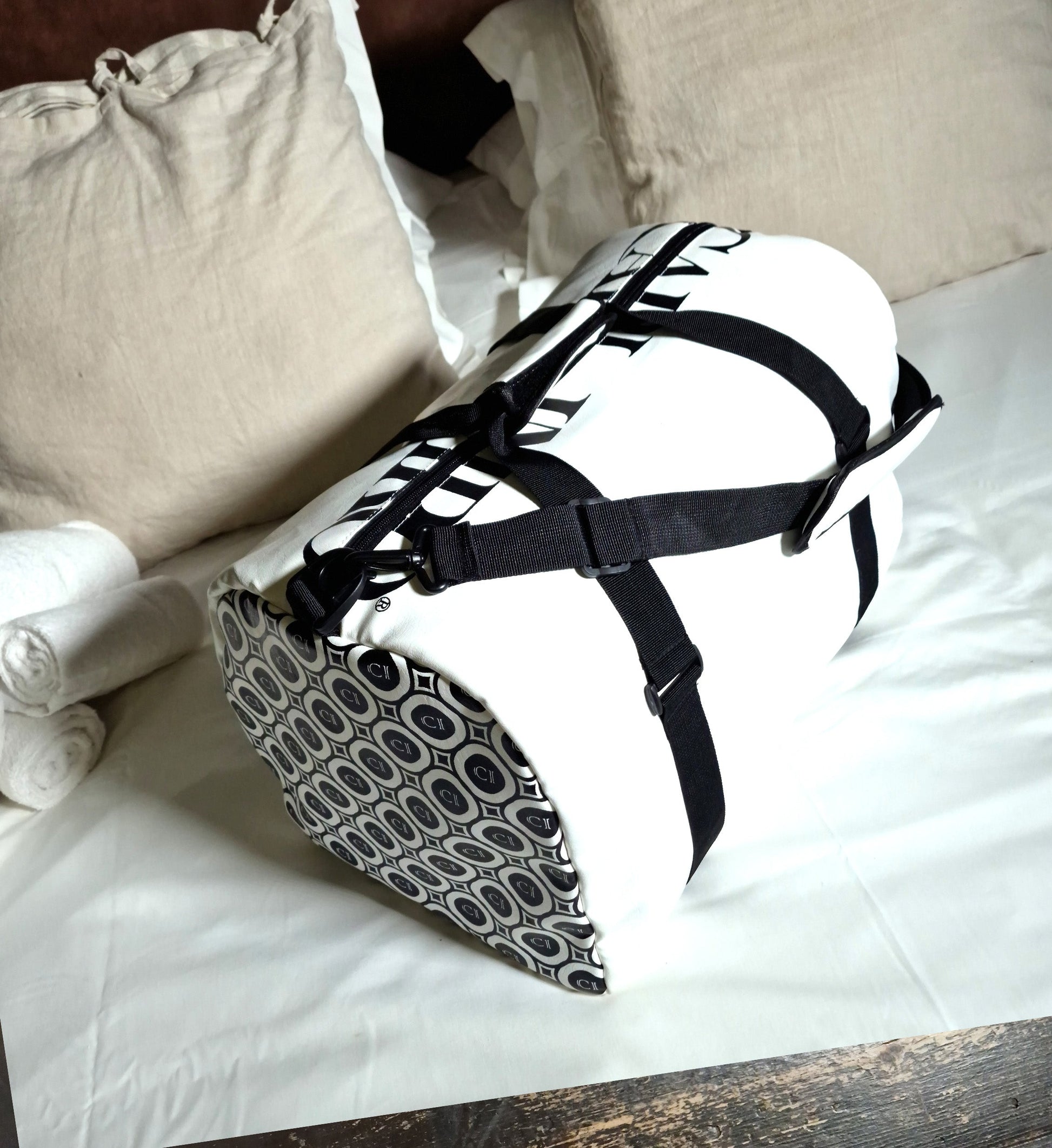 Sac en cuir blanc avec bandoulière noire et motifs de cercles sur le devant.