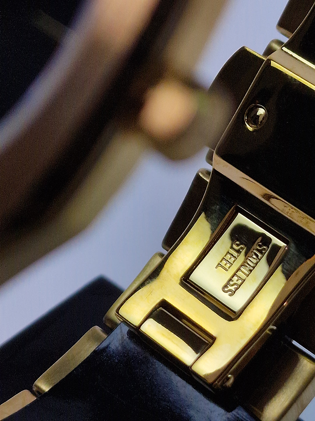 Fermoir de montre en acier doré, gravure et maillons du bracelet.