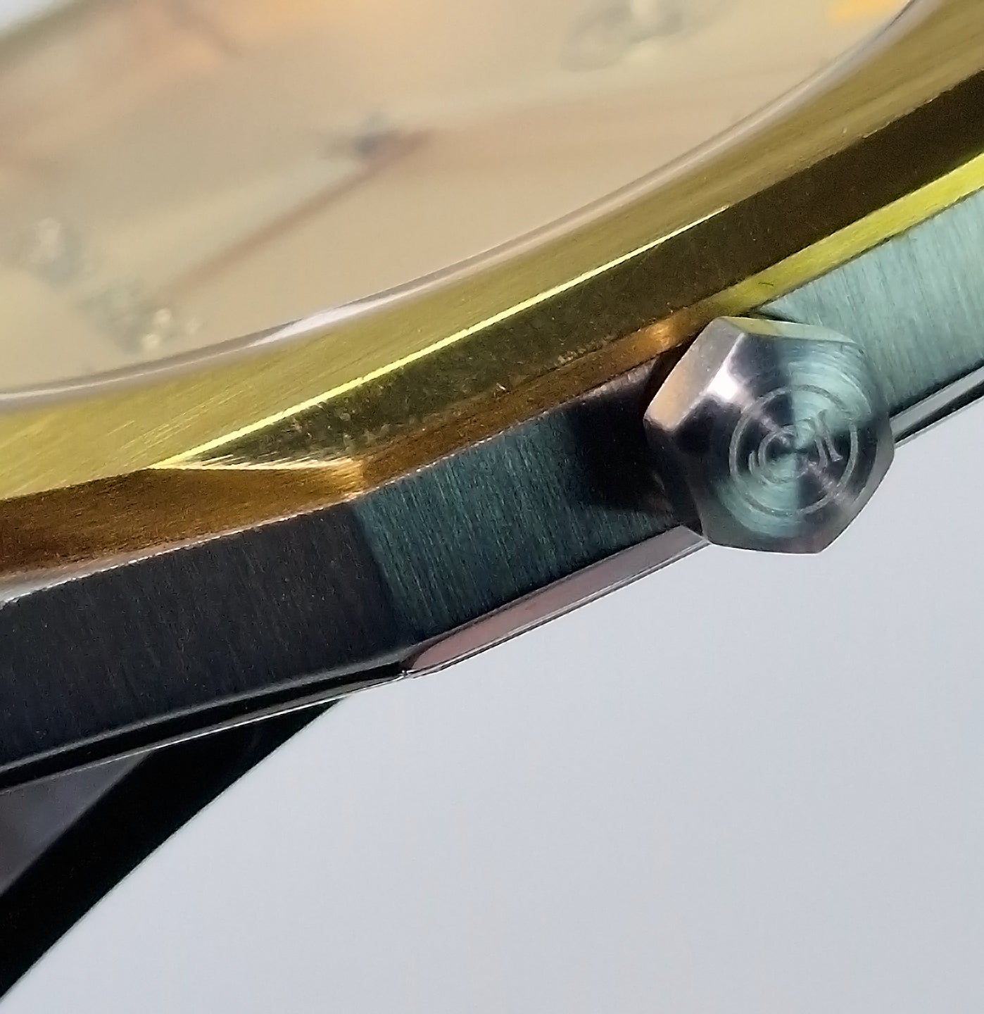 Couronne de montre bicolore en acier, finition dorée sur le côté du boîtier.