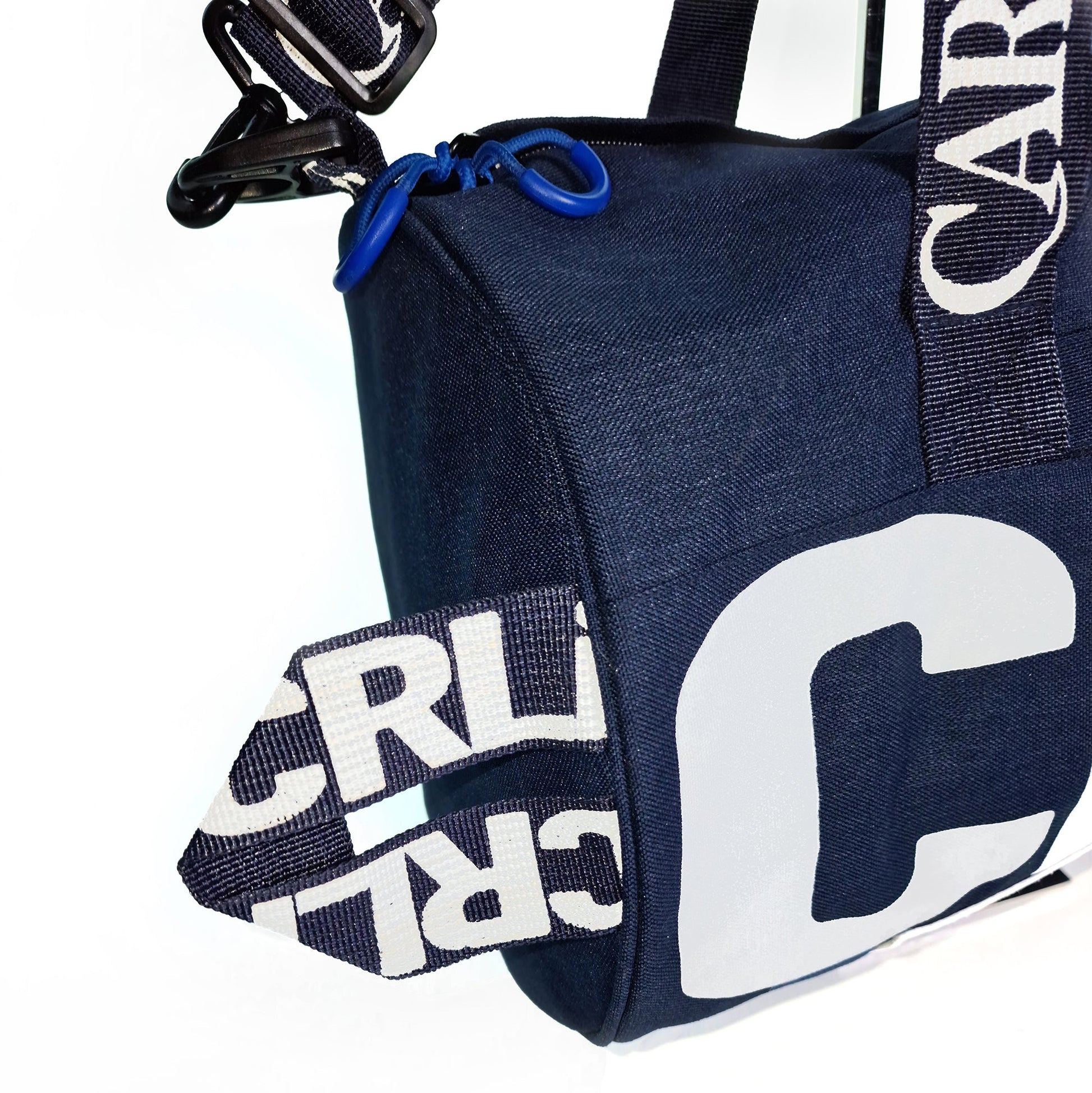 Sac en denim bleu, coin avec sangles et inscription CRLi sur le tissu.