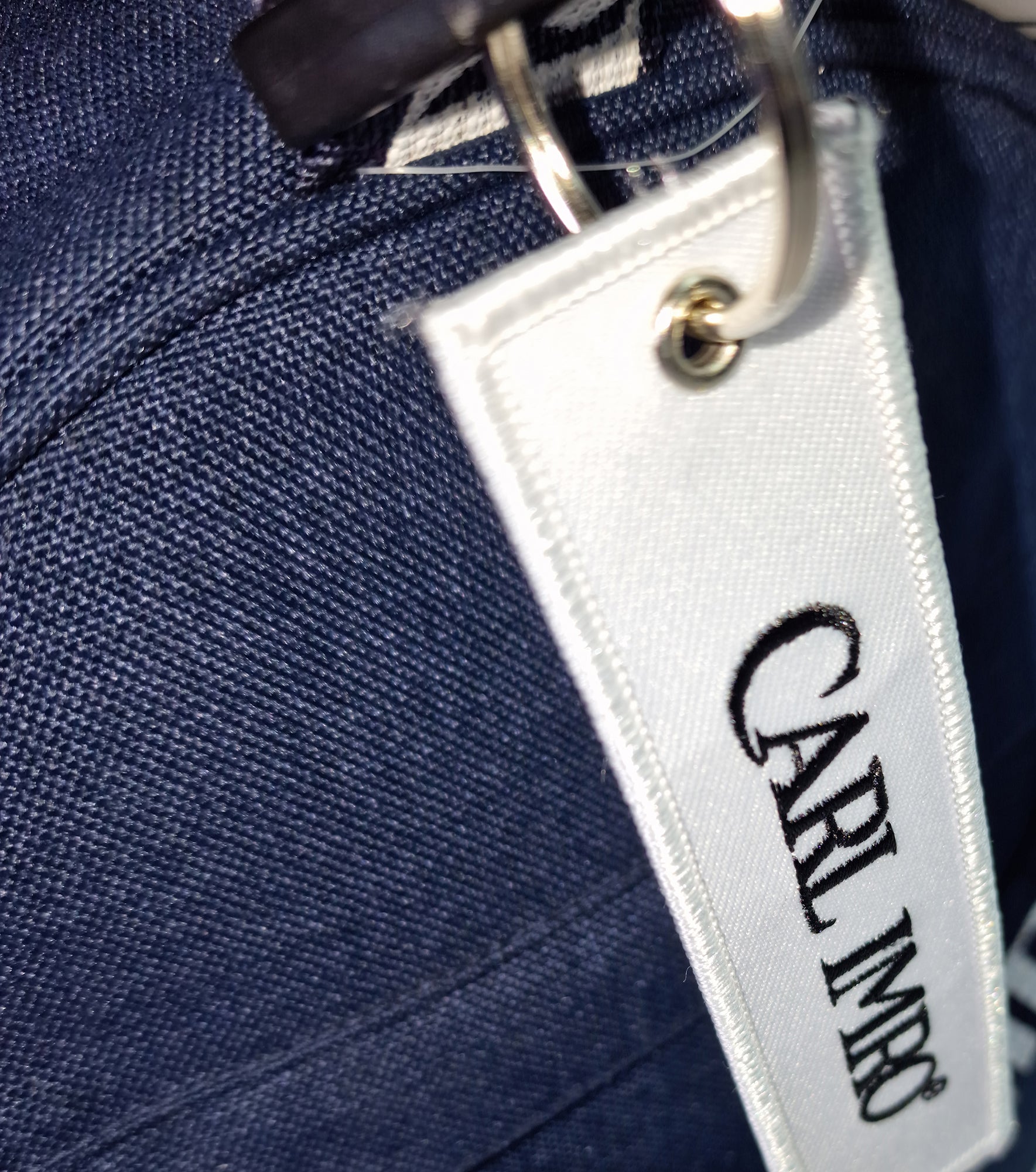 Étiquette CRLi sur sac duffel en denim bleu avec attache métallique.