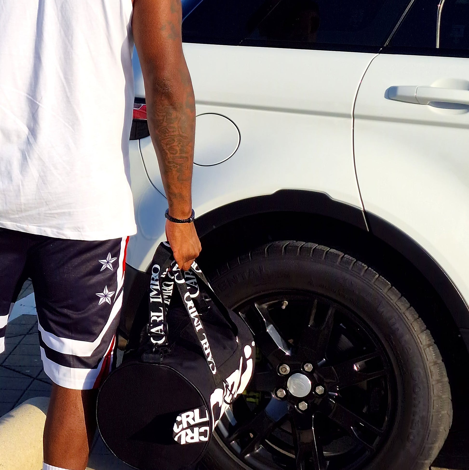 Sac de sport CRLi noir porté, bas avec logo blanc et sangles imprimées CARL IMRO