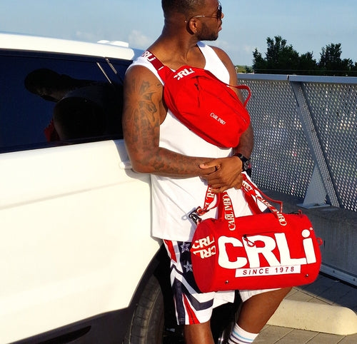 Sac bandoulière rouge en cuir synthétique, bandoulière avec détail logo.