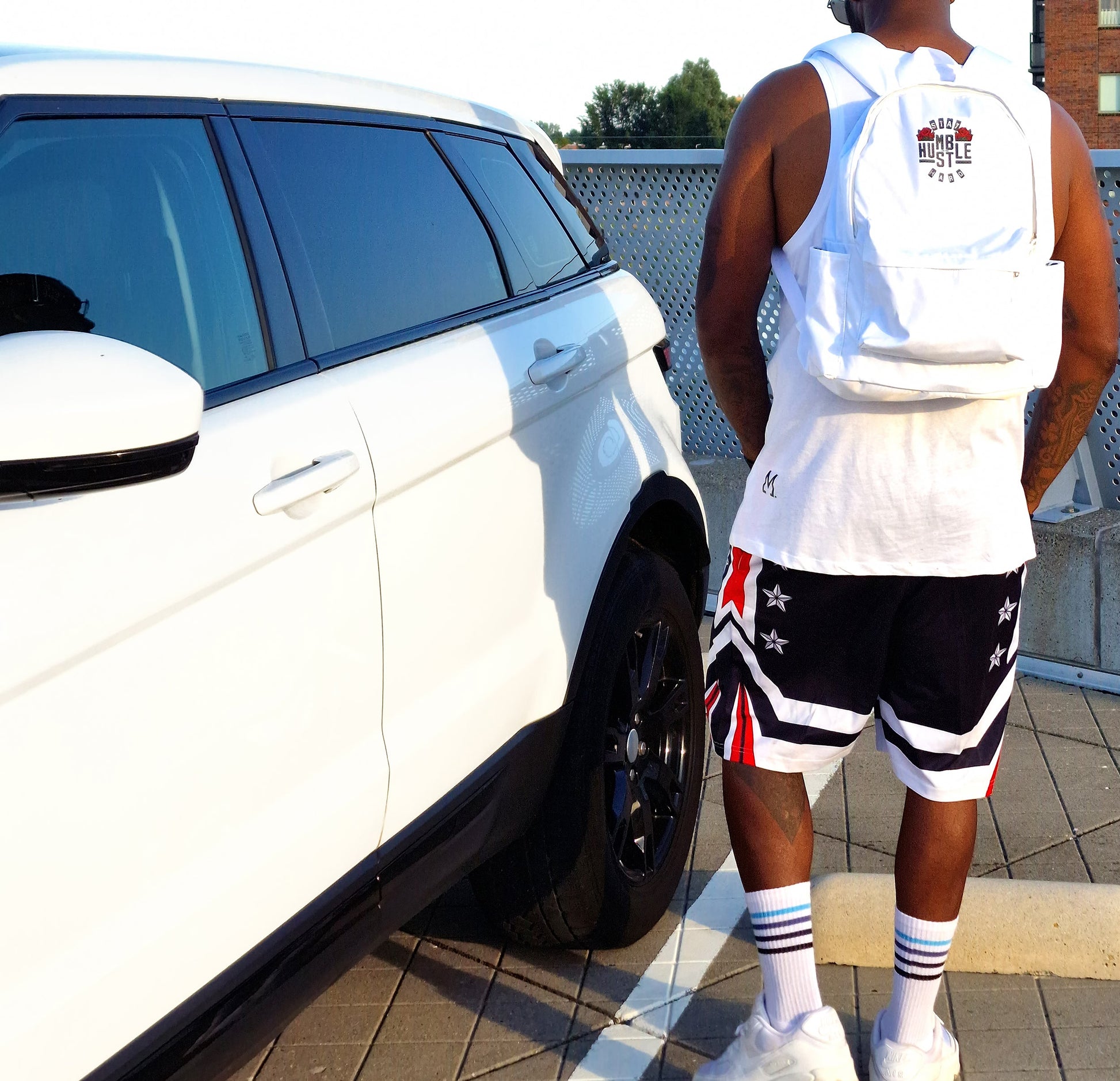 Sac à dos blanc porté au dos, logo « Hustle Hard » et sangles ajustables