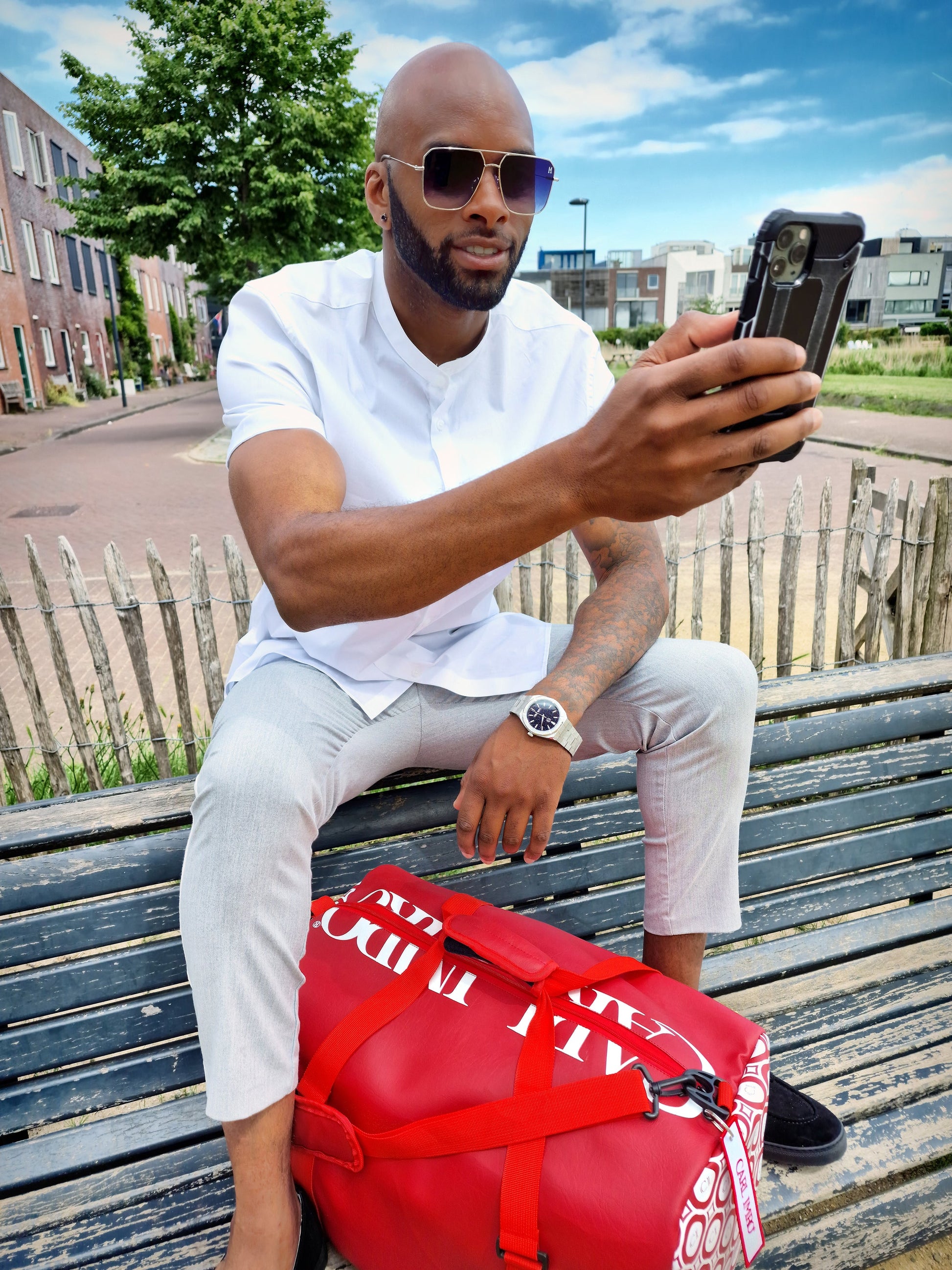 Sac en cuir rouge avec logo blanc, sangles noires et bandoulière