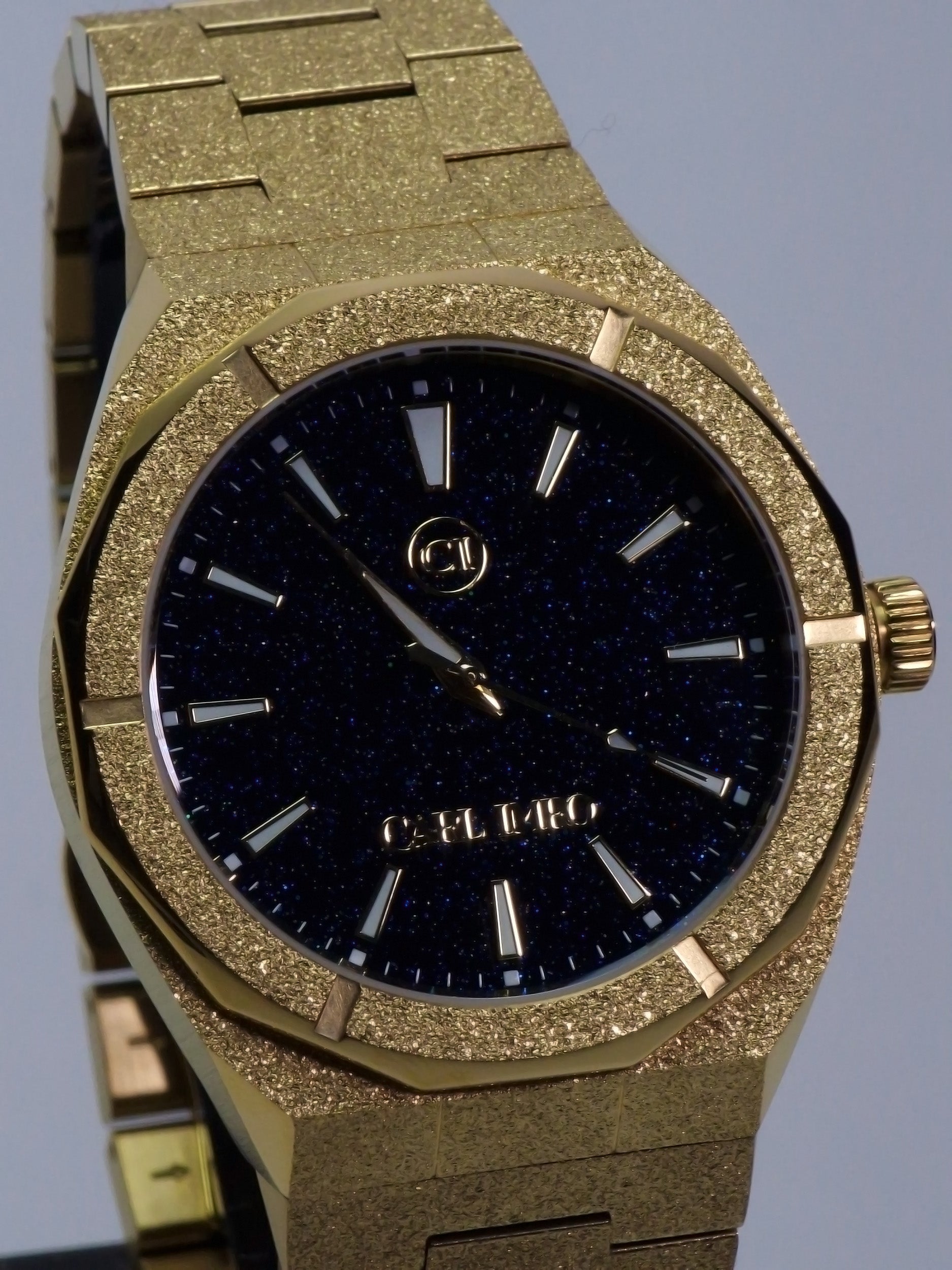 Montre homme bracelet acier doré texturé, cadran bleu nuit pailleté et index bâtons.