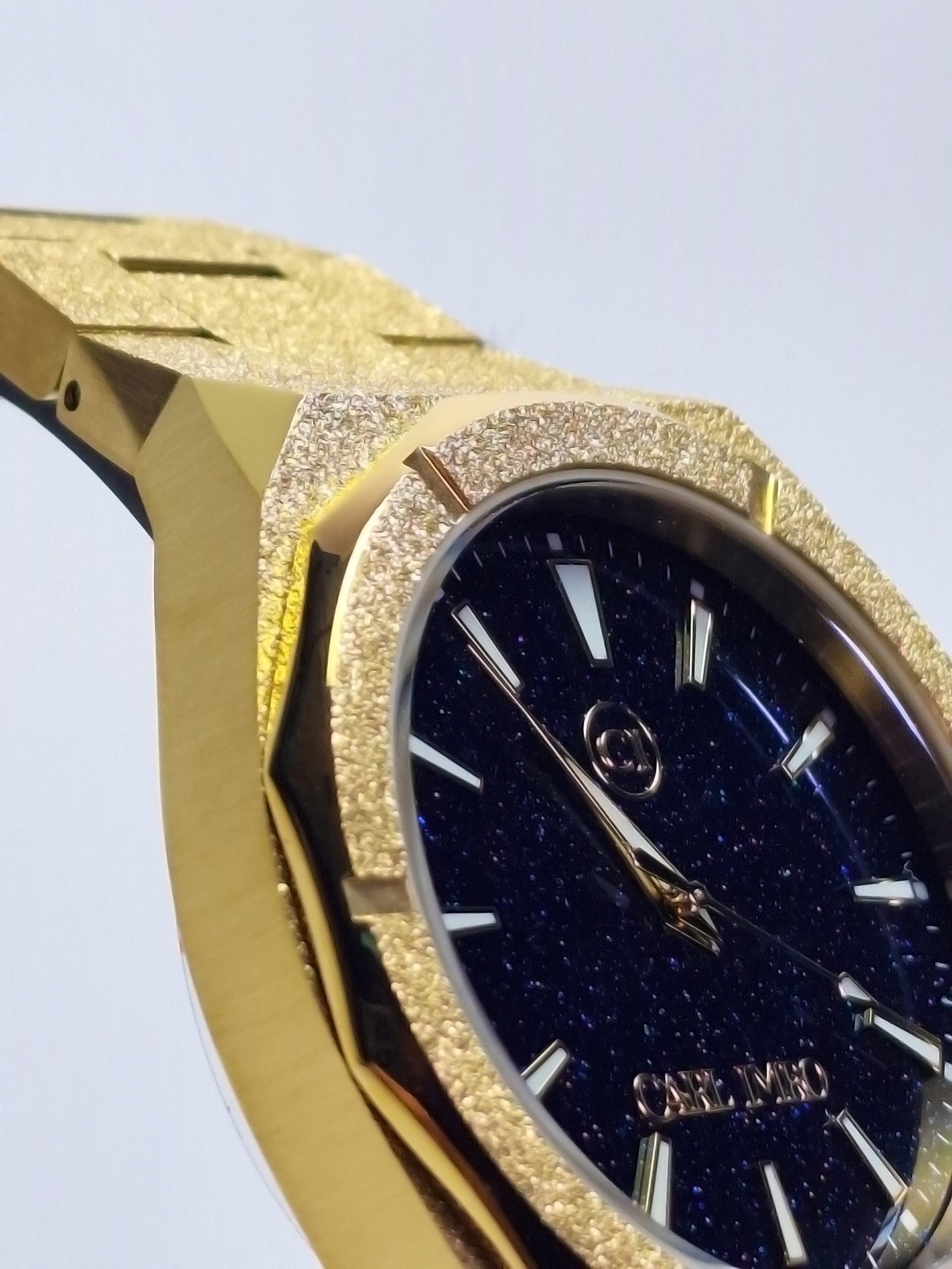 Montre homme : cadran bleu nuit pailleté, index bâtons dorés, lunette bordée de strass.