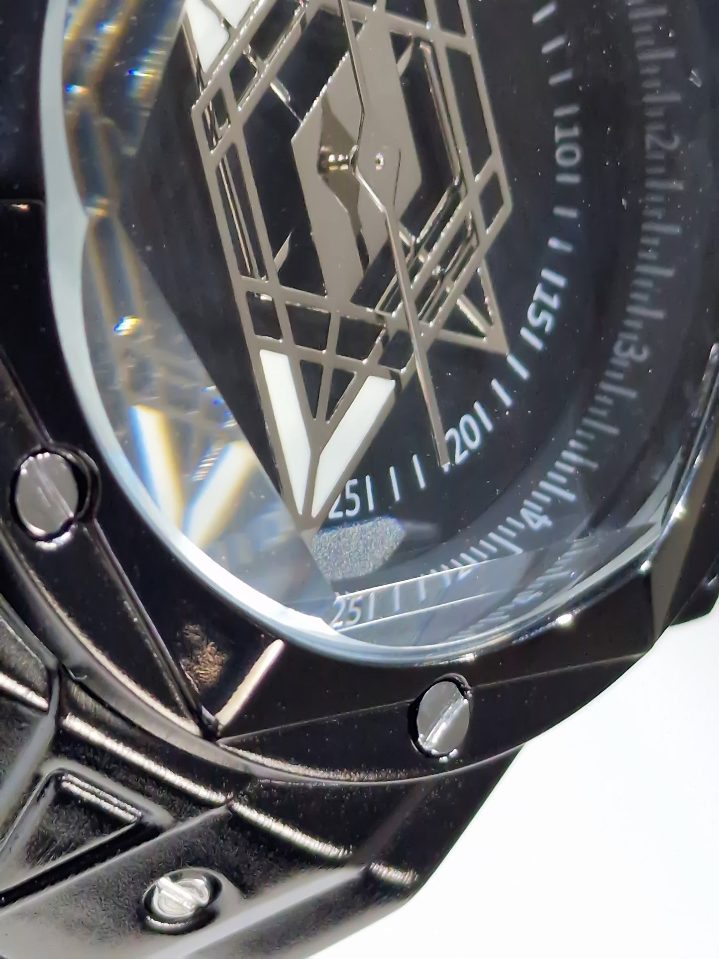 Gros plan cadran noir de la montre, détails géométriques et index blancs autour.