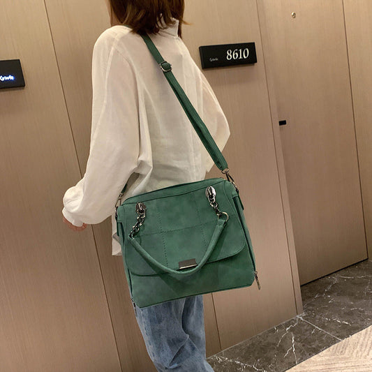 Sac à main en cuir synthétique vert porté en bandoulière, rabat avec fermeture