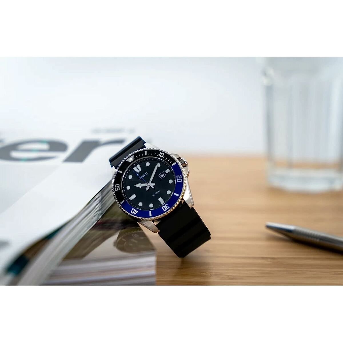 Montre diver sur bureau, cadran noir et bleu avec bracelet noir