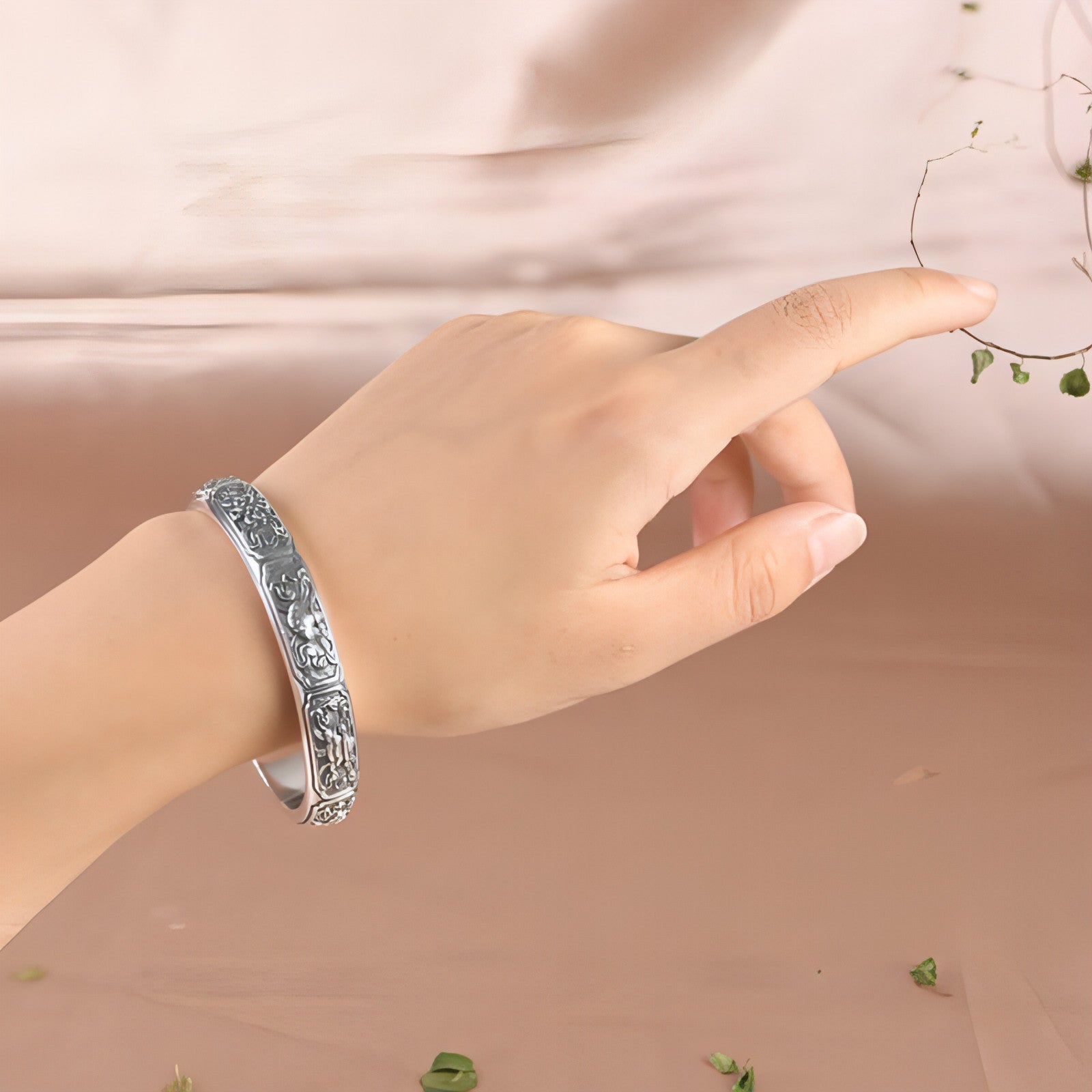 Bracelet manchette argent 999 porté au poignet, motifs gravés sur le pourtour.
