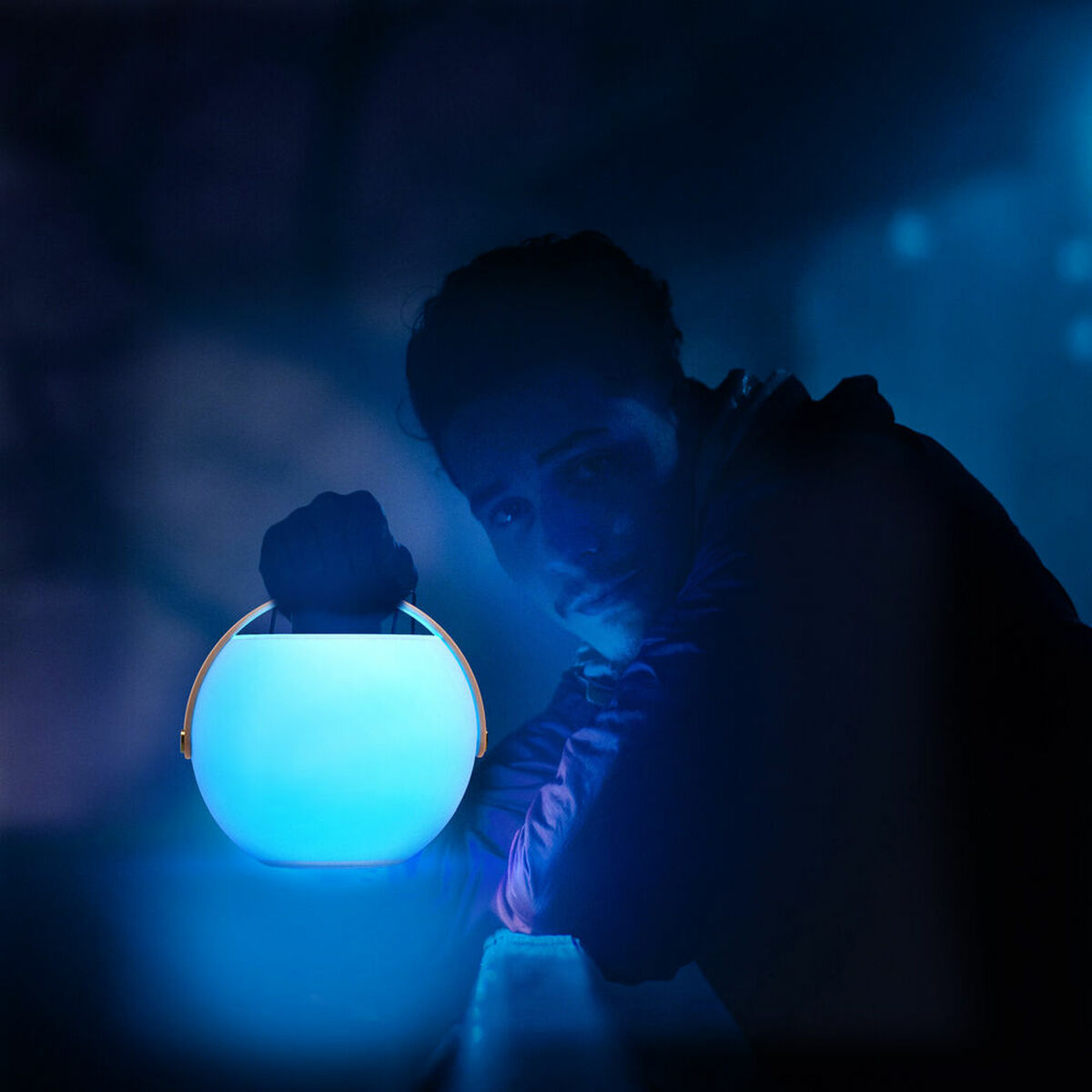 Enceinte Bluetooth portable ronde à lumière bleue, tenue à la main, design bulle.