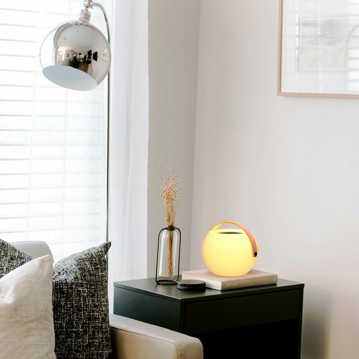 Enceinte Bluetooth portable ronde, lumière douce, dessus noir et poignée orange.