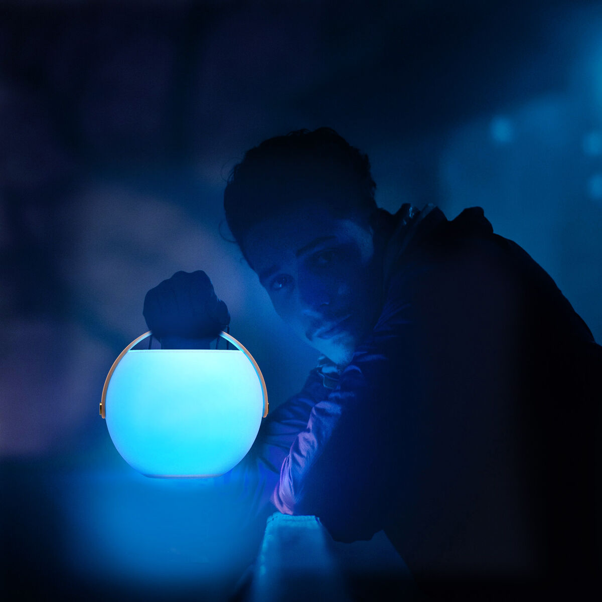 Enceinte bulle LED bleue allumée, lumière forte dans une scène nocturne.