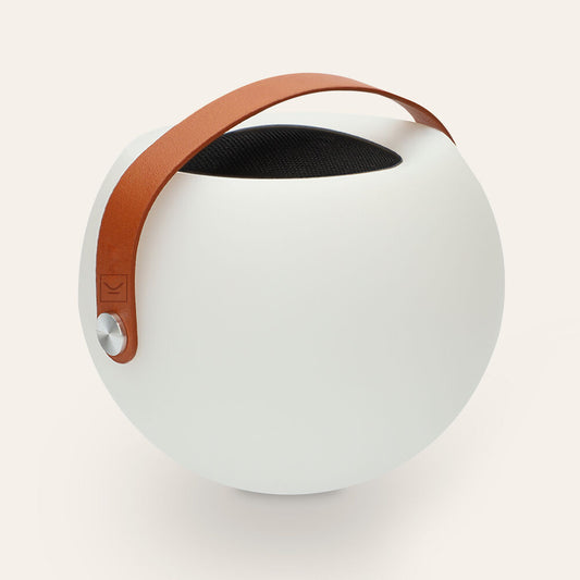 Enceinte Bluetooth portable blanche ronde, sangle marron et grille noire en haut.