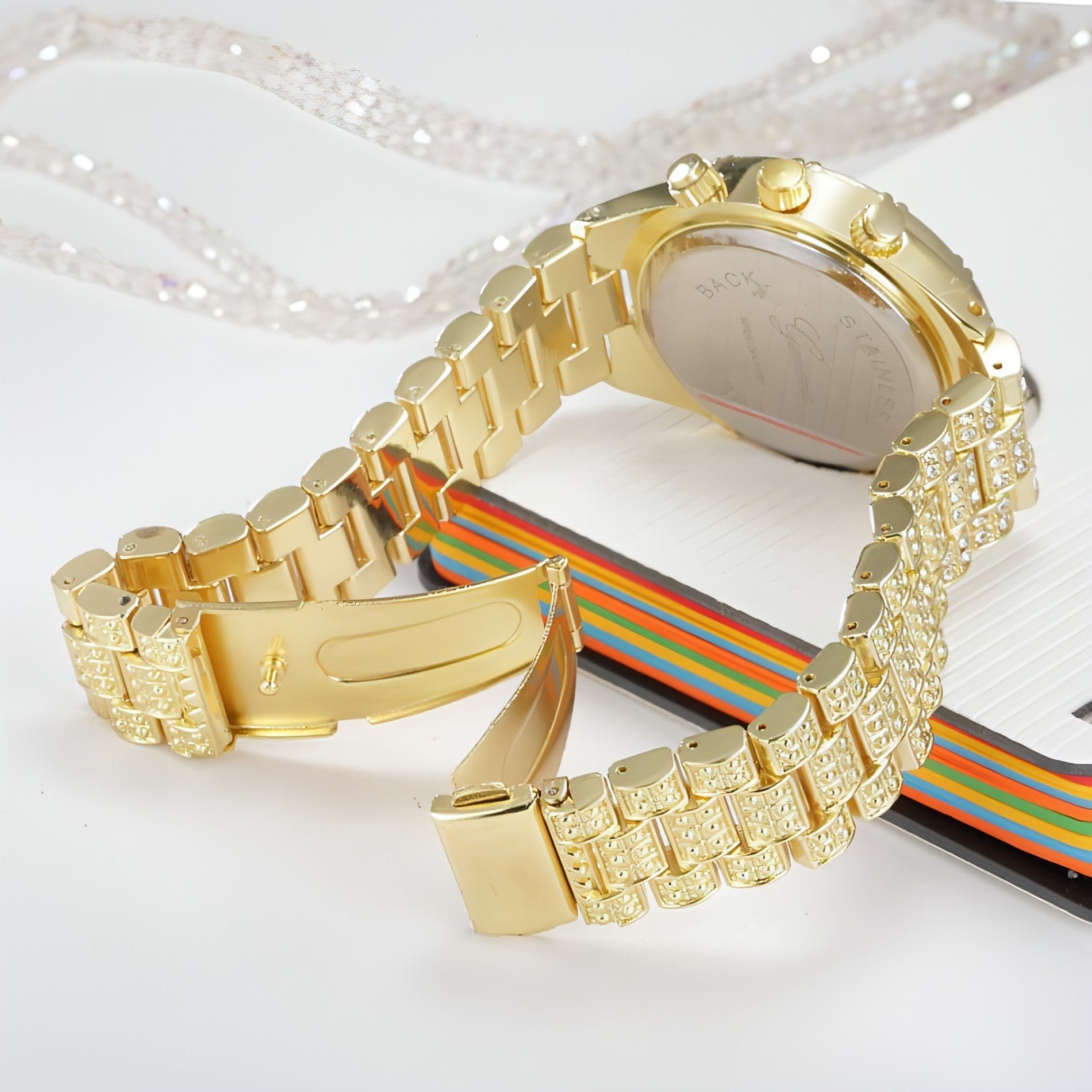 Montre femme dorée, boîtier et bracelet sertis, vue de profil avec couronne.