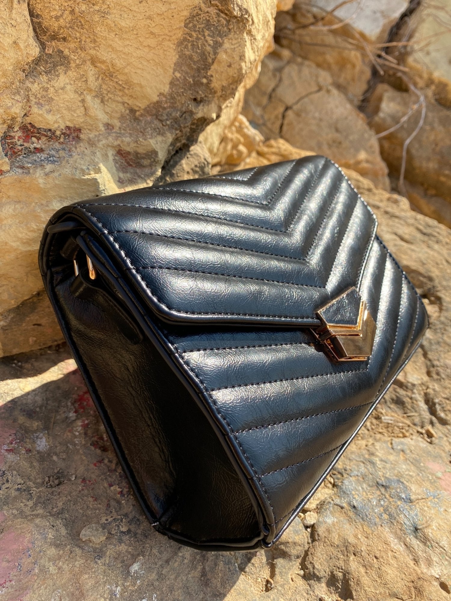 Sac bandoulière matelassé foncé, vue de côté avec rabat et fermoir métal doré