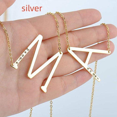 Collier en acier titane argenté avec pendentif lettres géométriques et chaîne fine.