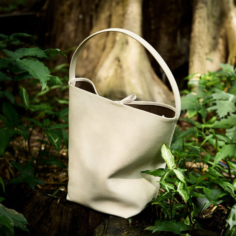 Sac seau en cuir Ideluxe™ beige clair, anses courbes, cordon visible, forme souple