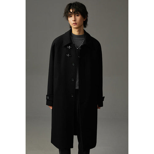 Manteau long en laine noir, col large, patte boutonnée avec boutons duffle et poches.