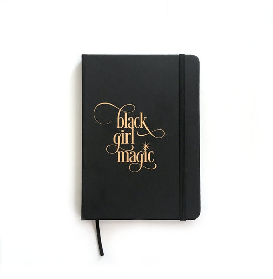 Carnet noir à couverture souple, lettrage doré « Black girl magic » et sangle