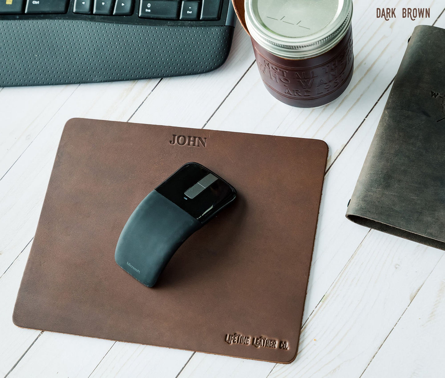 Tapis de souris en cuir marron foncé, bords arrondis et marquage John en haut