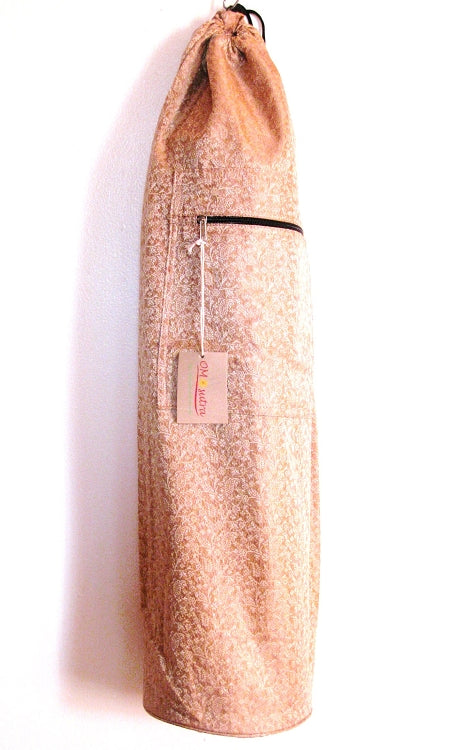 Sac de yoga cylindrique en tissu pêche, cordon de fermeture et sangle noire.