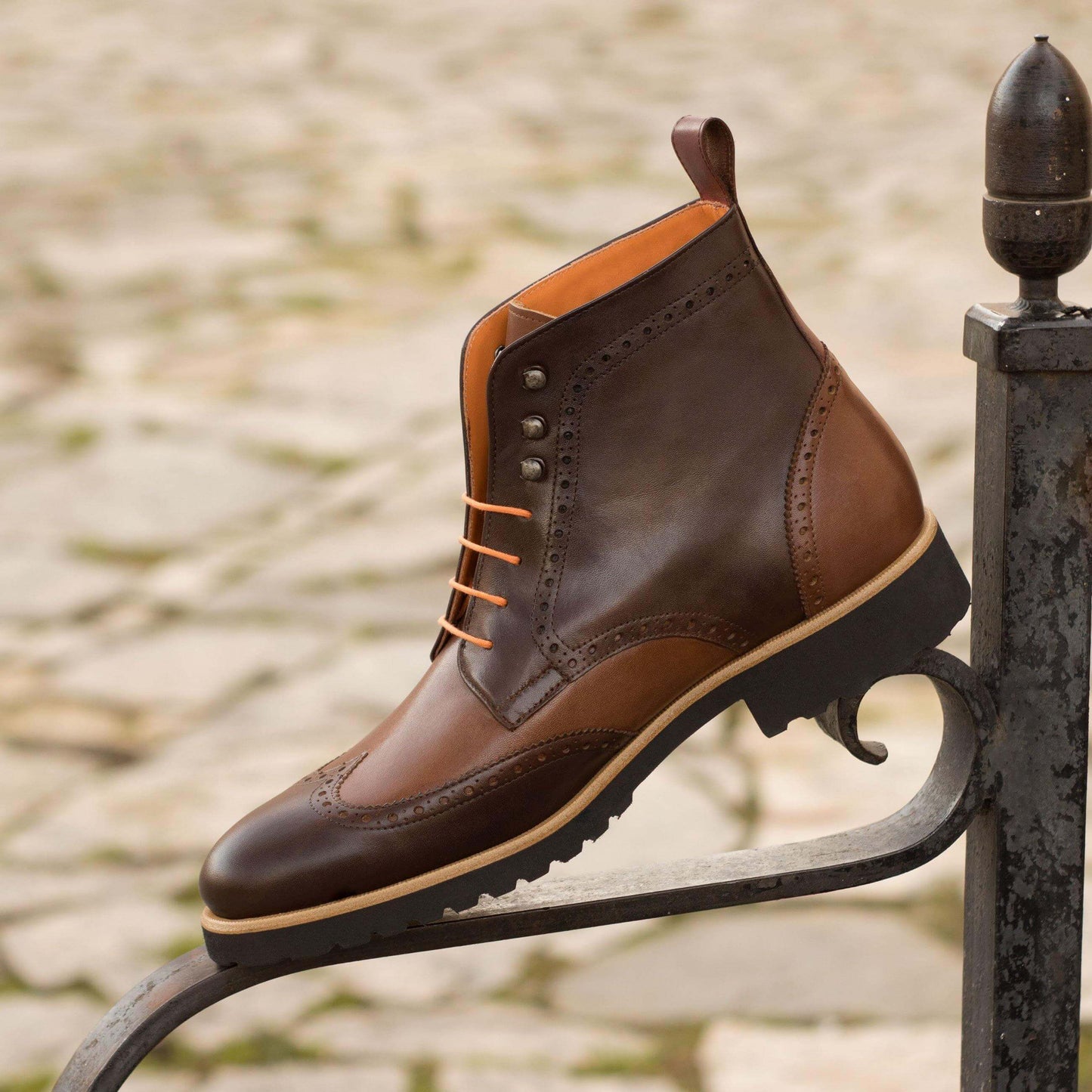 Botte brogue en cuir multicolore, lacets orange, posée sur garde-corps