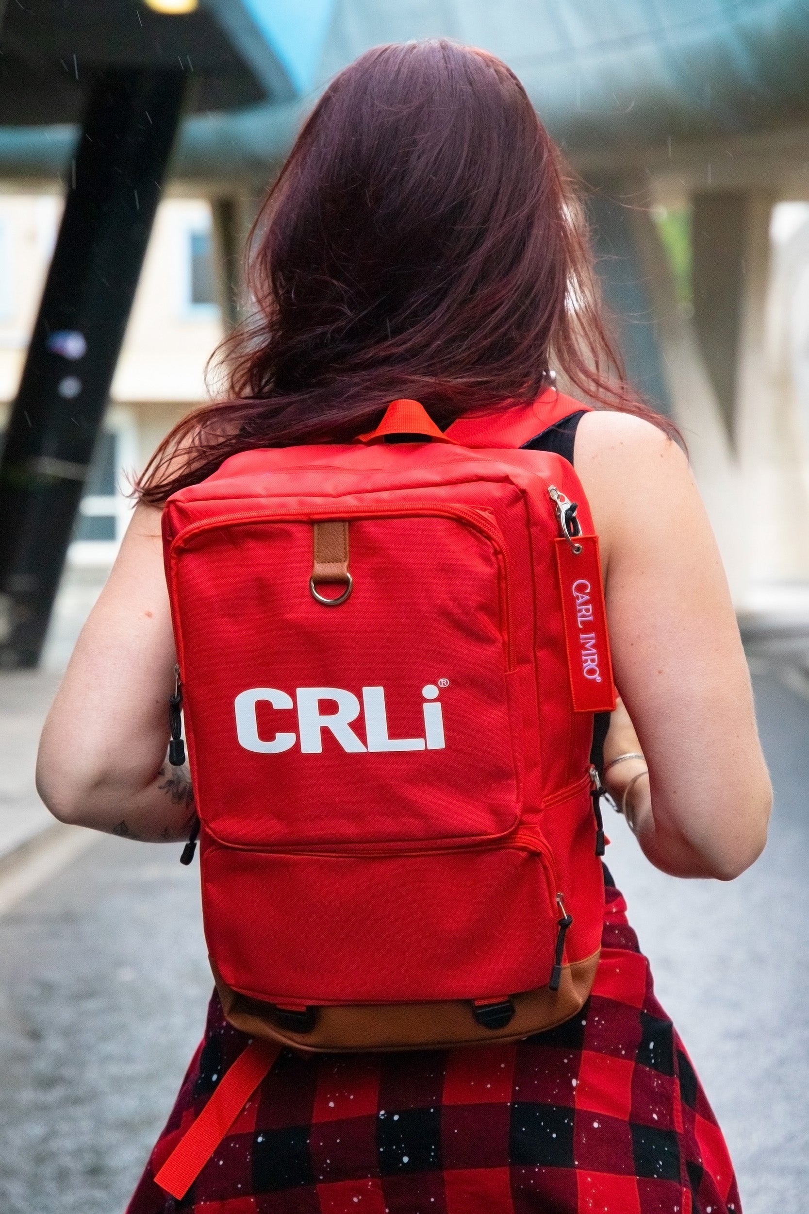 Sac à dos rouge avec logo CRLi à l’arrière, poche zippée et bretelles rembourrées.